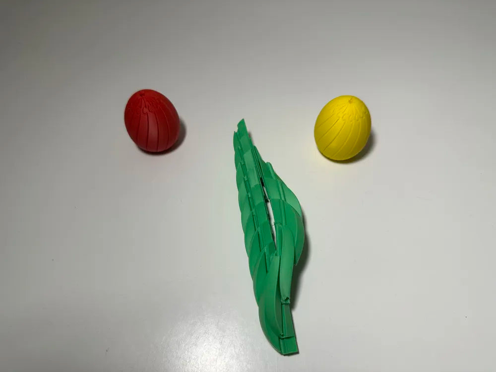 Huevos articulados flexibles impresos en 3D en rojo y amarillo con hoja verde articulada
