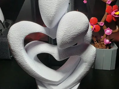 Escultura decorativa 3D de pareja abrazándose formando un corazón, color blanco con textura
