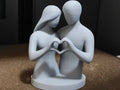 Escultura decorativa 3D pareja uniendo manos en forma de corazón, color gris claro, fondo oscuro