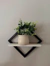 Estante rombo 3D negro con blanco instalado en pared con planta decorativa