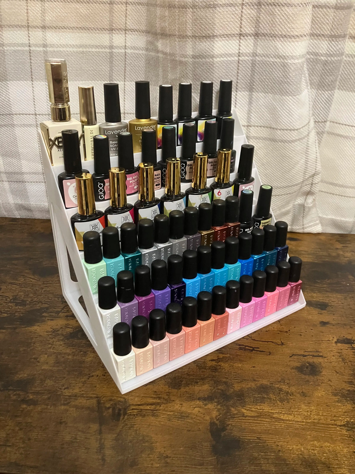 Exhibidor escalera 3D de 5 niveles color blanco con esmaltes organizados sobre mesa de madera
