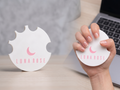 Nail swatch holder redondo impreso en 3D color blanco personalizado con nombre de salón, sostenido en mano con uñas nude