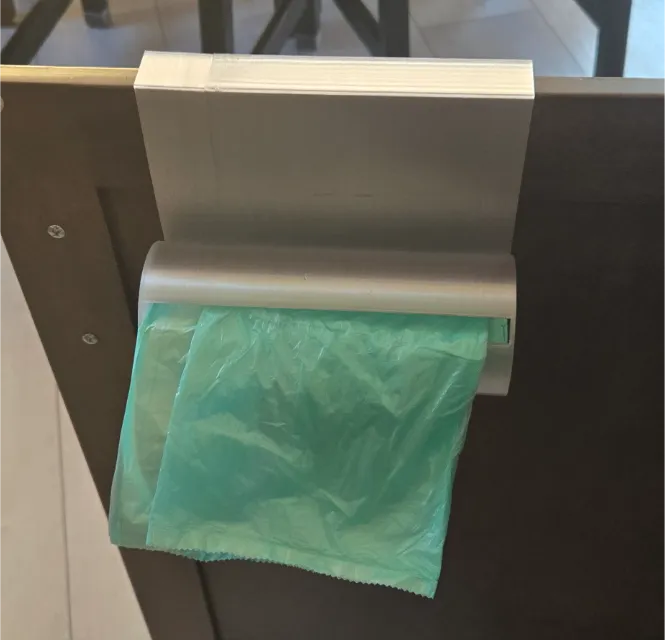Porta bolsas 3D impreso colgado en puerta de mueble de cocina con bolsa verde