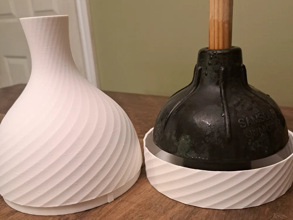Porta sopapa 3D blanco con textura en espiral junto a sopapa con funda puesta sobre mesa