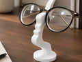 Soporte para anteojos 3D con forma de nariz y bigote color blanco sobre escritorio de madera